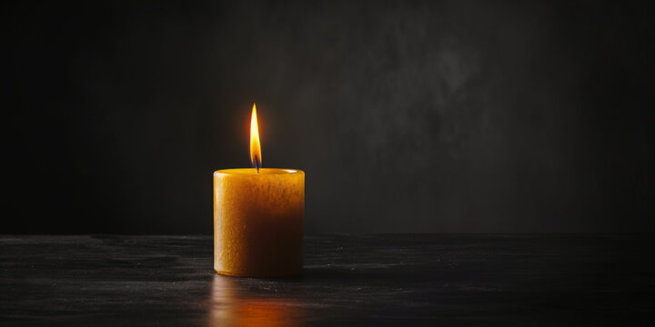 Single yellow candle with dark background for memorials, funerals, and obituaries concept with copy space