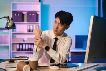 Tired office worker sitting at a desk using a computer and doing projects overtime in the lamplight.