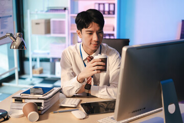 Obraz premium Business man using digital tablet analyzes business data, busy working on laptop computer with smart phone and business report on office desk, employees working overtime.