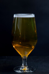 light golden beer in a glass glass on a black background