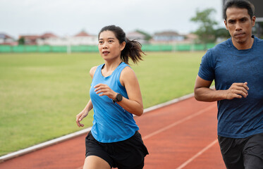 Obraz premium Asia mature woman and man runner training on racetrack and field 