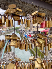 A lot of blurred locks of lovers on bridge on foreground and Naviglio channel in Milan on back