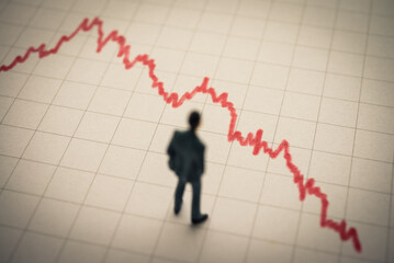 Businessman looking at falling down red graph tensely. Economy recession crisis, sales are falling,...