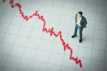 Businessman looking at falling down red graph tensely. Economy recession crisis, sales are falling,...
