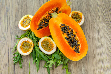 Papaya fruit, passion fruit and rucola on a light wooden background