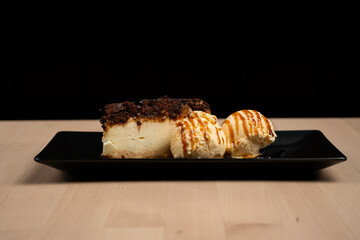 Delicious dessert plate with a slice of cheesecake and scoops of vanilla ice cream on wooden table