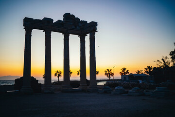 Fototapeta premium Side, Turkey. View from below of ancient ancient ruins of the Temple of Apollo with yellow sunset sky in the background during sunset. Manavgat, Turkey.