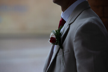 Groom wearing boutonniere with red and white roses on wedding day