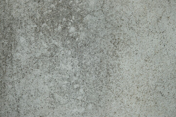 A grey and white wall with a rough texture. The wall is made of concrete and has a stone-like appearance