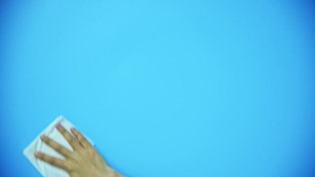 Hand holding paper towel for cleaning on blue background