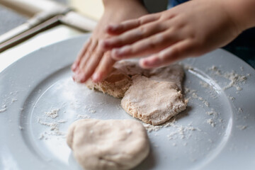 Child having fun modeling salt dough, authentic activity, fine motor skills development