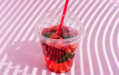 Strawberry lemonade with mint on pink background with beautiful shadows. Close-up. Selective focus.