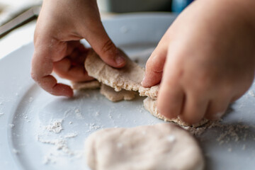 Child having fun modeling salt dough, authentic activity, fine motor skills development