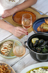 Young woman enjoiyng dinner in the Mediterranean restaurant. Glass of rose and various dishes served on the table.