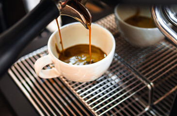 Close-up of espresso pouring from the coffee machine into a coffee cup. Professional coffee brewing