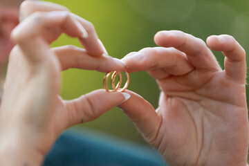 Couple holding wedding rings forming heart shape with fingers