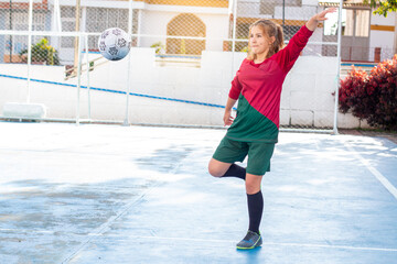 Concepts: women's sports and outdoor recreation. young woman playing soccer kicks the ball in the air. exercise and active lifestyle