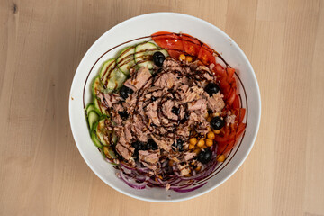 Top view of a fresh salad bowl with crispy chicken, cucumbers, tomatoes, and red onions