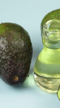 avocats et petite bouteille en verre d'huile, en gros plan, sur un fond bleu