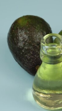 avocats et petite bouteille en verre d'huile, en gros plan, sur un fond bleu
