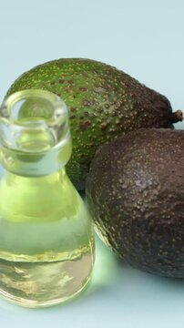 avocats et petite bouteille en verre d'huile, en gros plan, sur un fond bleu