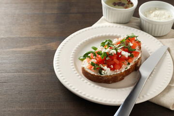 A sandwich in a plate on a dark wooden table.