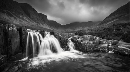 Majestic black and white landscape of cascading waterfalls surrounded by rugged mountain terrain.