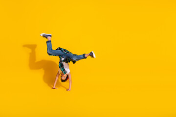Full body photo of cute little boy upside down handstand dressed stylish white clothes isolated on yellow color background © deagreez