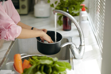 Close-up of woman washing rice under water in pan