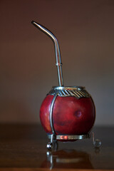 close-up of red mate with steel bombilla and silver details on wooden table, selective focus.