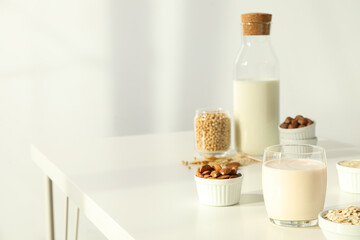 Bottle and glass of alternative milk and herbal ingredients on light background, space for text