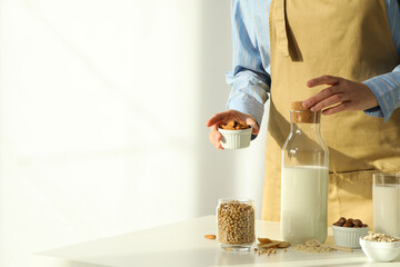 Man, bottle of alternative milk and herbal ingredients on light background, space for text