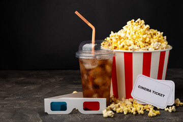 Tasty popcorn in buckets and cold cola drinks with cinema tickets, movie clapper and 3D eyeglasses...