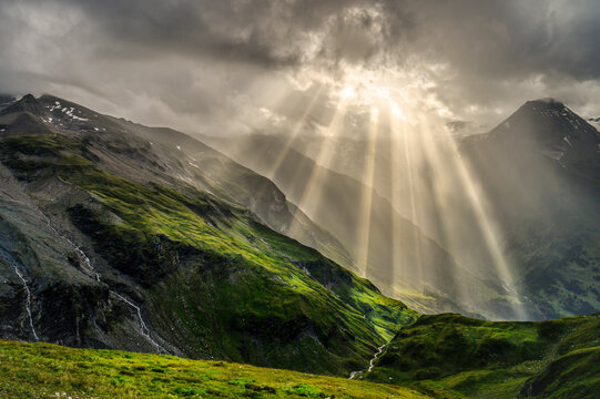 Nature and landscape in the spring. Landscape with dramatic sky and green meadows. The sun rays through the clouds. The Hohe Tauern mountain range, the valley below the hochalpenrstrasse.