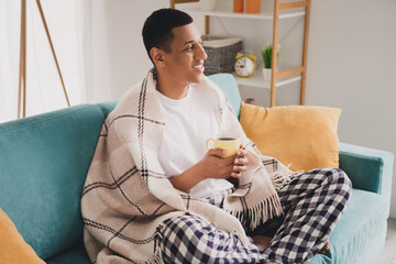 Photo of cheerful positive guy sleepwear pajama drink hot tea staying home sofa indoors house...