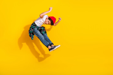 Obraz premium Full length photo of adorable little boy jumping pushing invisible things dressed stylish white garment isolated on yellow color background