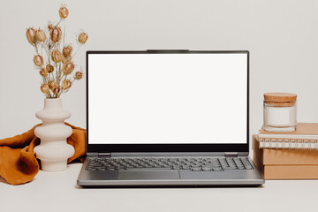 Mockup laptop with white screen and ceramic vase with dry bouquet, storage box, candle and notepad. Aesthetic laptop background for study, work, cozy hygge home office, web site promotion