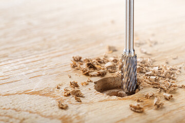 end mill makes a hole in the wooden oak table with wood