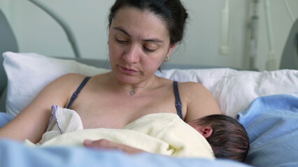 Mother breastfeeding newborn in hospital bed, showcasing maternal care, nurturing, and the intimate...