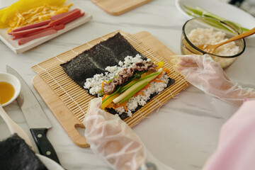 High angle view of woman in gloves making kimbap from meat and vegetables © DragonImages
