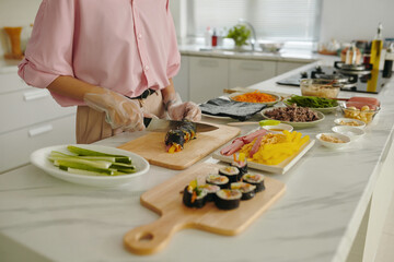 Housewife in gloves making homemade kimbap in the kitchen © DragonImages