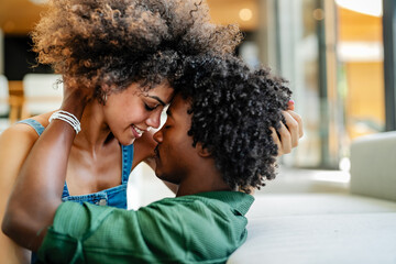 A young cheerful couple of African descent lying on a couch of a modern living room having an...