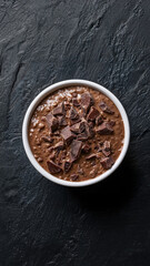Delicious Chocolate Oatmeal with Chunks in White Bowl on Dark Background