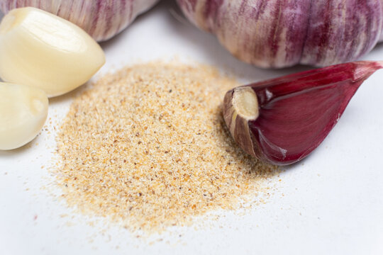 Ground dried garlic powder, natural spice, white background.