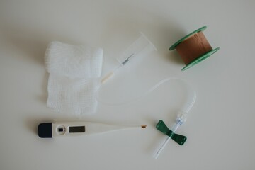 butterfly needle for drawing blood, thermometer, skin-colored tape and white bandage on a...