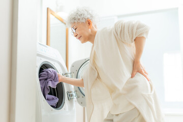 洗濯で腰痛に苦しむシニア女性
