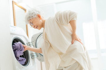 洗濯で腰痛に苦しむシニア女性