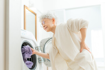 洗濯で腰痛に苦しむシニア女性 © folyphoto