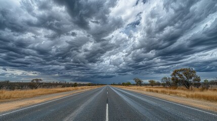 Straight line of Matilda Highway under the vast cloudy skies in Queensland