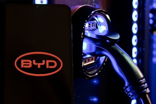 The logo of BYD Automobile Co Ltd displayed on mobile phone, BYD  an automotive company of the People's Republic of China, electric charger on the background.